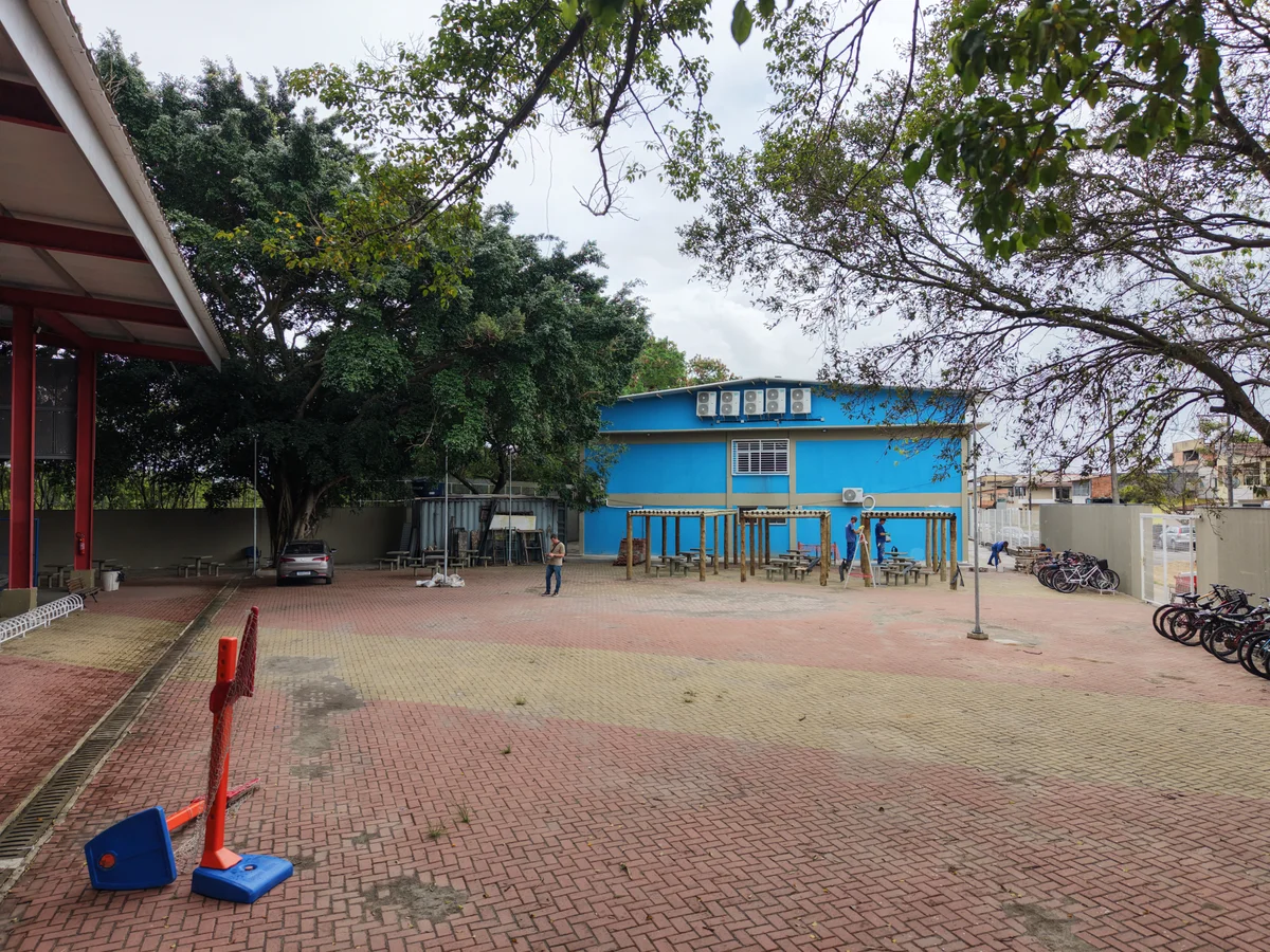 Pátio externo pavimentado entre a quadra e o bloco escolar